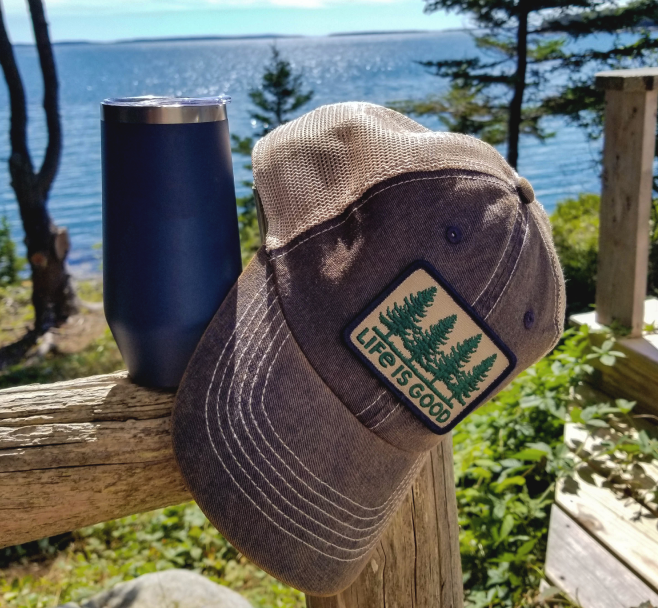 Fencepost overlooking a lake, with a coffee mug and hat placed on the fence