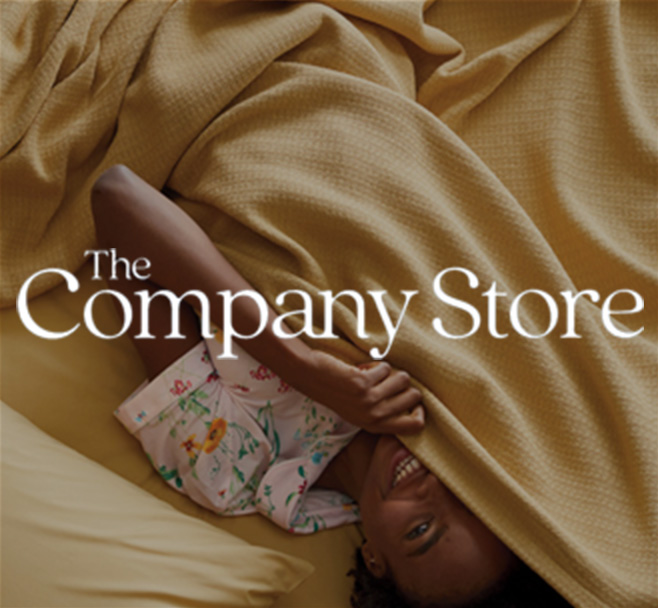 The Company Store: Smiling child peeking out from under pale yellow sheets