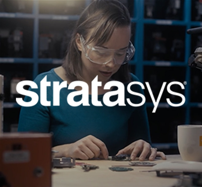 Stratasys: person sitting at workbench wearing safety goggles